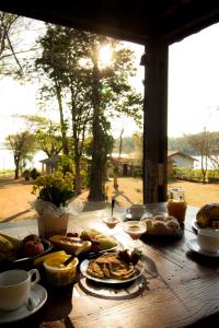 - une table en bois avec des aliments pour le petit-déjeuner et une fenêtre dans l'établissement Casa de Campo em frente ao Lago em Americana-SP, à Americana