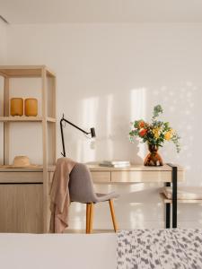 einen Schreibtisch mit einem Stuhl, einer Lampe und einer Vase aus Blumen in der Unterkunft MIM Mallorca Member of Melia Collection in Sa Coma + 39 Fotos