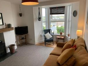 ein Wohnzimmer mit einem braunen Sofa und einem Fenster in der Unterkunft 'Langton' - Best Views in Falmouth! in Falmouth
