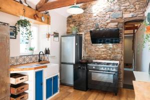 eine Küche mit einem schwarzen Kühlschrank und einer Steinwand in der Unterkunft 'Langton' - Best Views in Falmouth! in Falmouth