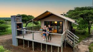 eine Familie steht vor einem winzigen Haus in der Unterkunft AfriCamps at White Elephant Safaris in Pongola Game Reserve