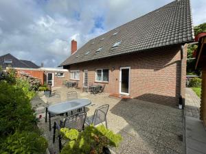 Un patio con sillas y una mesa y una casa. en Haus Achtern Diek - Ferienwohnungen, en Wangerland