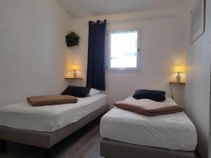 deux lits dans une chambre avec une fenêtre dans l'établissement Le Petit Port du Loiron 17 Charente Maritime, à Angoulins-sur-Mer