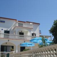 budynek z dwoma niebieskimi parasolami przed nim w obiekcie B&B Villa Sofija w mieście Grebaštica
