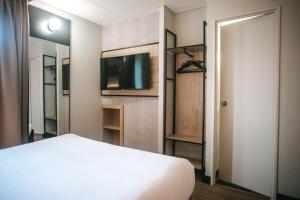 a bedroom with a bed and a flat screen tv at ibis Limoges Centre in Limoges