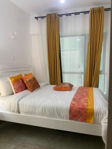 Una cama blanca con almohadas naranjas en un dormitorio en Purespace Luxury, en Nairobi