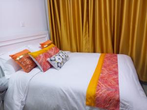 a white bed with colorful pillows on top of it at Purespace Luxury in Nairobi