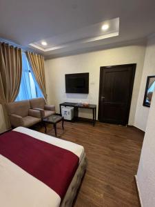 a hotel room with a bed and a couch and a television at Crescent Hotel in Peshawar