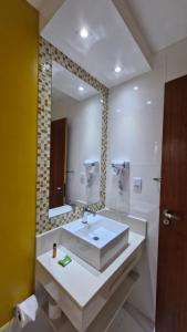 a bathroom with a sink and a large mirror at pousada essência in Paraty