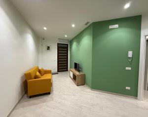 a living room with a yellow couch and a green wall at Maison Rovaga in Ispica