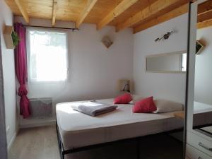 a bedroom with a bed with red pillows and a window at La pointe du Chay in Le Pavé
