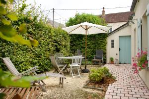eine Terrasse mit Tisch und Stühlen und einem Sonnenschirm in der Unterkunft Le Cabanon in Cosne Cours sur Loire