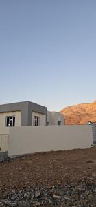 un edificio con una pared blanca en un campo en إطلالة غروب الشمس, en Misfāh
