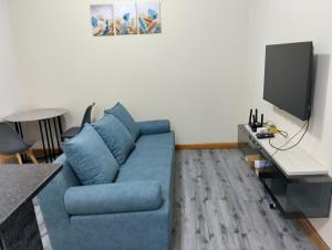 a living room with a blue couch and a tv at Mutamba Central in Luanda