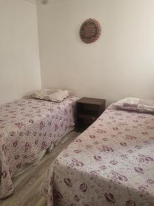a bedroom with two beds and a clock on the wall at Departamento elsa ramitez in Ovalle