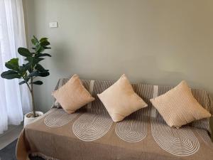 a couch with four pillows on it in a living room at Surfers Shell Dahican in Dahikan +13 photos
