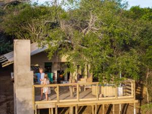 a woman and child standing on the deck of a house at AfriCamps at Bonamanzi Game Reserve in Hluhluwe