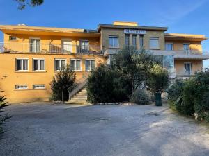 ein großes gelbes Gebäude mit Parkplatz in der Unterkunft Logis Hôtel Le Clement V in Roquemaure