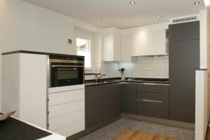 a kitchen with white cabinets and a black appliance at Apartments Weid in Leukerbad