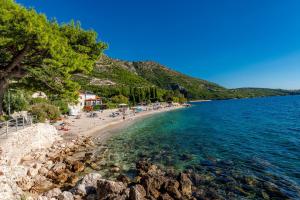ein Strand mit einer Gruppe von Menschen und dem Wasser in der Unterkunft Silvio Beach House - Shoreline Haven in Mlini
