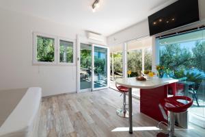 eine Küche mit einem Tisch und einigen Stühlen und Fenstern in der Unterkunft Silvio Beach House - Shoreline Haven in Mlini