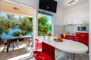 eine Küche mit roten Schränken und einem großen Fenster in der Unterkunft Silvio Beach House - Shoreline Haven in Mlini