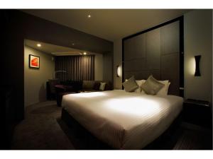 una camera d'albergo con un grande letto e un soggiorno di Hotel Trusty Nagoya Shirakawa a Nagoya