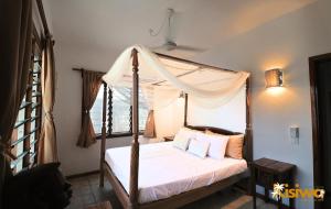 a bedroom with a canopy bed with white sheets and pillows at Kisiwa Apartments Watamu - At Ascot Resort - in Watamu +47 photos