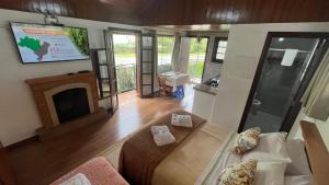 ein Wohnzimmer mit einem Bett und einem Kamin in der Unterkunft Chalés Ipe Amarelo in Camanducaia