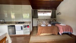 a small bedroom with a bed and a kitchen at Chalés Ipe Amarelo in Camanducaia