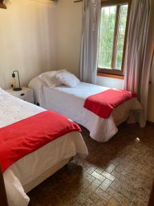 a bedroom with two beds with red and white sheets at Duplex la 70 in San Clemente del Tuyú