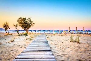 a wooden pathway through the sand on a beach at Perla Nera Villa Mit Privatem Beheiztem Pool in Kávallos