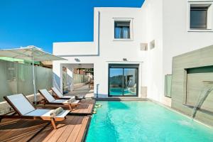 a house with a swimming pool with chairs and an umbrella at Perla Nera Villa Mit Privatem Beheiztem Pool in Kávallos