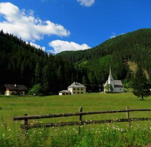 un champ vert avec une clôture en bois devant une montagne dans l'établissement Gemütliches Ferienhaus In Ruhiger Lage, à Innerkrems
