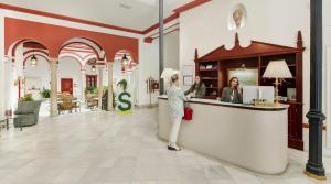 a woman is standing at a counter in a store at Sercotel Las Casas de los Mercaderes in Seville