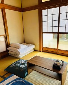 a room with a bed and a table andwindows at Kia Ora Setouchi in Shodoshima