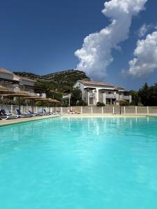 a large swimming pool with blue water and chairs at Beautiful 2 bedroom apartment with pool in Saint Florent in Oletta