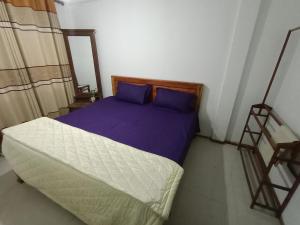 ein Schlafzimmer mit einem Bett mit violetter Bettwäsche in der Unterkunft Diyatalawa Mountain Holiday Resorts in Diyatalawa