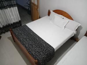 ein Schlafzimmer mit einem Bett mit weißen Laken und Kissen in der Unterkunft Diyatalawa Mountain Holiday Resorts in Diyatalawa