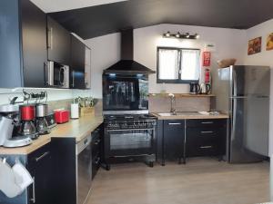 une cuisine avec des armoires noires et un four à plaques de cuisson dans l'établissement Villa 1893, à Le Pavé 8 autres photos