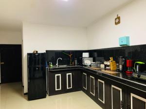 a kitchen with black cabinets and a black refrigerator at Conch Villa- 3 Min walk to the beaches in Tangalle +20 photos