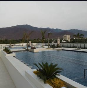 圣玛尔塔Frente al mar ,vista panoramica, acceso a la playa的一座棕榈树和山脉环绕的游泳池