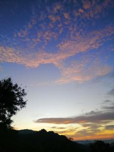 a sunset with a tree in the foreground at Super View Home Stay in Ella