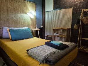 a bedroom with a yellow bed with blue pillows at Baan Koody Hostel in Ko Kut