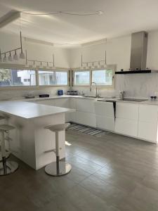 a kitchen with white cabinets and a sink and stools at Villa Malù in Lignano Sabbiadoro +5 photos