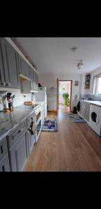 une cuisine avec des armoires blanches et un plancher en bois dans l'établissement Home in Thurso NC500, à Thurso