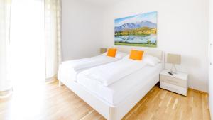 a white bed in a white room with orange pillows at Stilvolles Appartment Für Sechs Personen in Unterburg am Klopeiner See