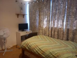 ein Schlafzimmer mit einem Bett und einem Schreibtisch mit einem Fernseher in der Unterkunft Ahmadiyya in 