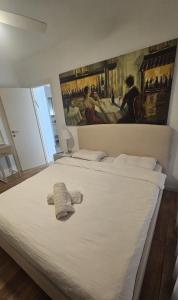 Un dormitorio con una gran cama blanca con un cuadro en la pared. en הבית בשביל הזהב, en Cesarea 2 fotos más