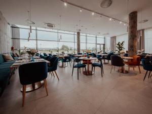 a restaurant with tables and chairs and large windows at Arche Hotel Lotnisko Gdańsk in Gdańsk-Rębiechowo